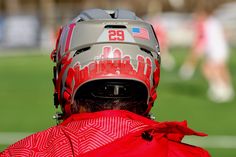 the back of a person wearing a helmet with an american flag on it and other people in the background