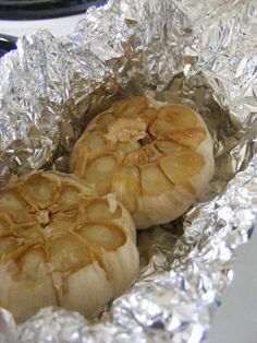 two peeled onions sitting in foil on top of a stove