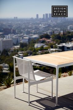 a table and chair sitting on top of a cement floor next to a cityscape