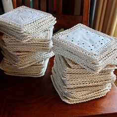 a stack of white crocheted napkins sitting on top of a wooden table