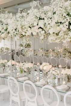 an elegant wedding reception with white flowers and tall glass vases on the side tables