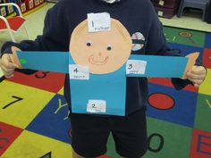 a young boy holding up a cut out of paper with numbers on it in front of him