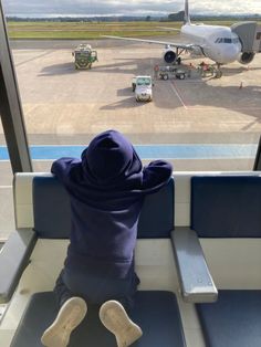 a person sitting on a bench looking out an airport window