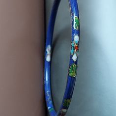 A classic bangle in cloisonne' enamel. VINTAGE 1970's collectible. Layer and stack bracelet. Rich imperial blue...a dramatic shade of indigo, with an almost purple tone. Floral accents are red, green, and gold. Nicely textured surface, and beveled edge. Complement your Autumn style, tweeds, silks, denim. Slim wrist size. 1970's. Gift boxed. VINTAGE Inner Circle: 2-1/2" Width: 3/16" Retro Enamel Bracelets For Gifts, Retro Enamel Bracelets For Gift, Retro Enamel Bracelet For Gift, Vintage Handmade Enamel Bangle, Handmade Vintage Enamel Bangle, Vintage Enamel Bangle As A Gift, Vintage Enamel Bangle For Gift, Vintage Enamel Bangle As Gift, Vintage Enamel Bangle Gift