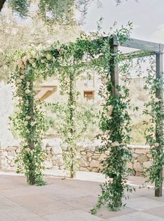 an outdoor wedding ceremony with greenery on the arbor