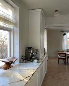 an empty kitchen with marble counter tops and white cabinets, along with wooden dining room tables