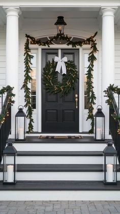 a front porch decorated for christmas with wreaths and lanterns