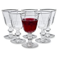 four wine goblets with red liquid in the middle, all lined up on top of each other