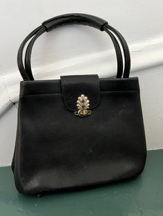 "Vintage 50s leather Park Lane top handle purse. This Park Lane purse has buttery leather, and a unique metal clasp. The interior features a zippered pouch. The handles feature a braided lacing look for extra pizazz, lest you think it's just a simple, little, black purse. There are some age related flaws, such as slight scuffs on the leather (featured in last pic), and metal on the back turning green (featured in second pic), as well as a bit on the clasp (see third pic),  but the metal part cou Vintage Top Handle Shoulder Bag For Party, Vintage Evening Satchel With Leather Handles, Retro Formal Shoulder Bag With Leather Handles, Vintage Formal Satchel With Hasp Closure, Vintage Leather Satchel For Evening, Vintage Leather Evening Satchel, Vintage Shoulder Bag With Brass Hardware For Evening, Vintage Black Shoulder Bag, Vintage Evening Bags With Leather Handles