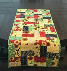 Cheerful, handmade sunflower patchwork table runner featuring sunflower florals in shades of yellow, green, red and black. The backing fabric is a matching sunflower print from the same fabric line. This table runner would bring a cheerful and striking splash of color to any room, perfect for sunflower lovers! Size is 16" X 40" Runner has been professionally quilted in an all-over floral pattern. The double fold binding has been hand sewn to the front for a professional appearance. Care instructions: The easiest way to clean your runner is to just vacuum it. If you want a deeper cleaning, wash gently in cold water; tumble dry on low (or air dry to prevent shrinkage). Iron as necessary. This runner was machine pieced and quilted by me in my smoke free home studio. Please don’t hesitate to c Christmas Tree Quilt Block, Tree Quilt Block, Pinwheel Quilt Block, Handmade Sunflower, Christmas Tree Quilt, Patchwork Table Runner, Cat Cuddle, Pinwheel Quilt, Professional Appearance