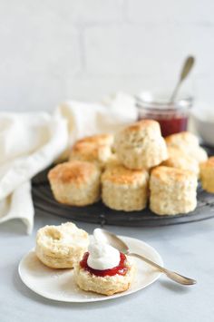 scones with butter and jam on a plate next to a jar of jelly sauce