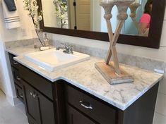 a bathroom with marble counter top and double sink area, mirror above the vanity is a woman taking a selfie