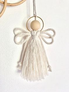 an angel is hanging on the wall next to two rings and a wooden bead