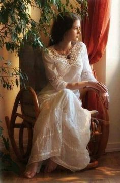 a woman sitting in a rocking chair next to a window