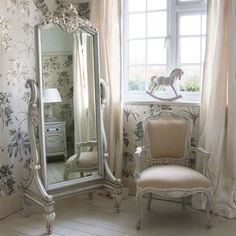 a chair and mirror in a room with floral wallpaper on the walls, along with a horse statue