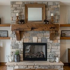 a living room with a stone fireplace and wooden shelves on either side, along with a mirror above the fire place