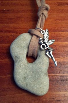 a rock with a silver charm attached to it on a wooden table next to a cord