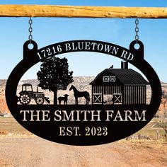 the smith farm sign is hanging from a wooden pole in front of a dirt road