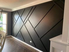 a dining room with wood floors and black wallpaper on the walls, along with white chairs