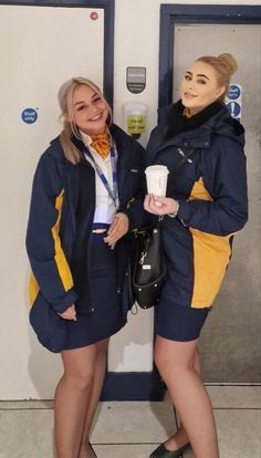 two women standing next to each other holding drinks