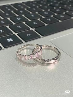 two wedding rings sitting on top of a laptop keyboard