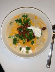 a white bowl filled with soup sitting on top of a table next to a spoon