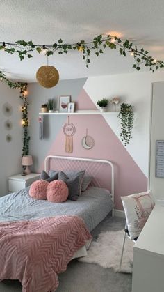 a bedroom decorated in pink and grey with plants on the wall above the bed, along with other decorations