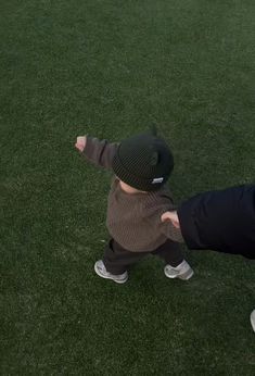 a man holding the hand of a small child who is reaching for a frisbee