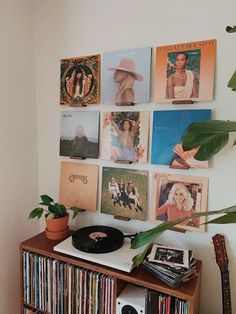 a record player sitting on top of a wooden shelf next to a wall covered in records