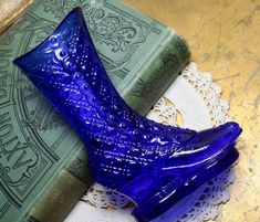 a blue glass boot sitting on top of a doily next to a green book