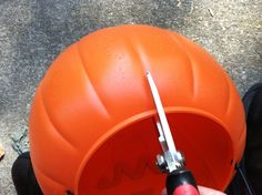 a person is holding a screwdriver in front of an orange ball