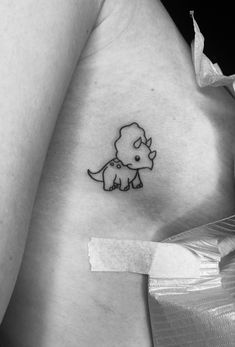 a woman's stomach with a small tattoo of a dinosaur on her left side