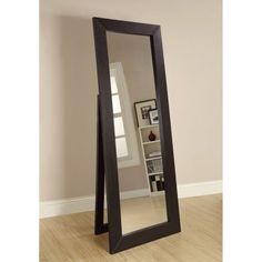 a large mirror sitting on top of a wooden floor in front of a white wall