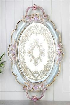 an ornately decorated mirror hanging on the wall next to a potted green plant