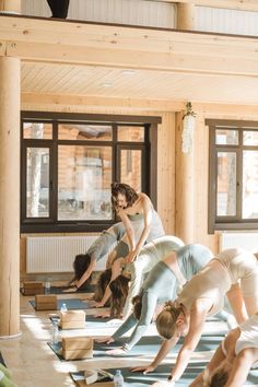 a group of people doing yoga on mats in a room with wooden walls and windows