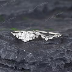 an engagement ring on top of a rock with leaves and flowers in the middle, surrounded by stones