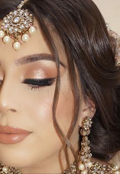 a woman wearing a bridal outfit and jewelry with her eyes closed to the side