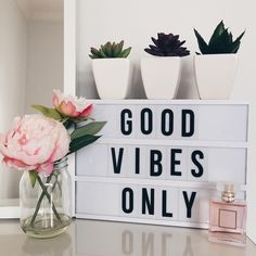 a sign that says good vibes only with flowers in front of it on a table