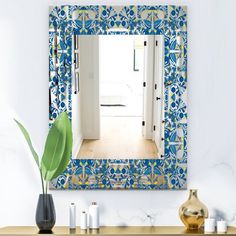 a blue and yellow mirror sitting on top of a wooden table next to a vase