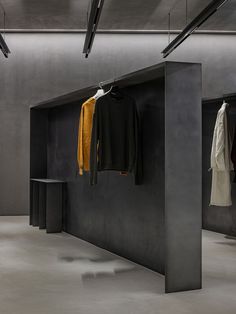 an empty room with clothes hanging on the wall and two coats hung up in front of it