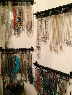 there are many necklaces hanging on the wall next to a bucket and trash can