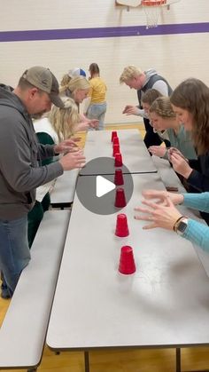 a group of people standing around a table with red cones on it and one person holding out their hands