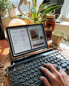 a person typing on an old - fashioned typewriter in front of a potted plant