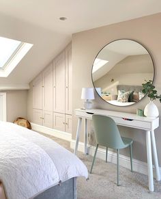 a bedroom with a bed, desk and mirror on the wall next to an attic window