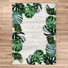 a white area rug with green leaves on the floor in front of a wooden floor