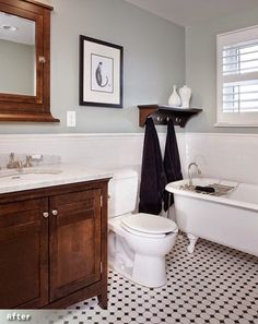 a white bath tub sitting next to a toilet under a bathroom mirror on top of a wooden cabinet