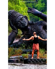 a man standing in front of a statue with his arms spread out to the side