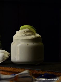 a jar of whipped cream with a lime slice on top and a spoon next to it