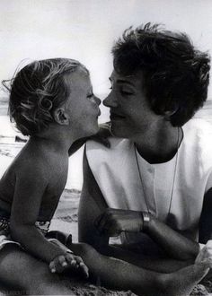 a woman kissing a small child on the beach