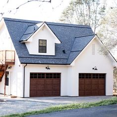 a white house with two brown garage doors